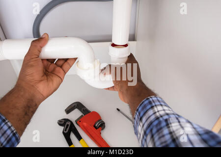 Close-up Of Plumber Fitting Sink Pipe In Kitchen At Home Stock Photo