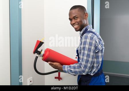 Happy Male African Professional Holding Fire Extinguisher Stock Photo