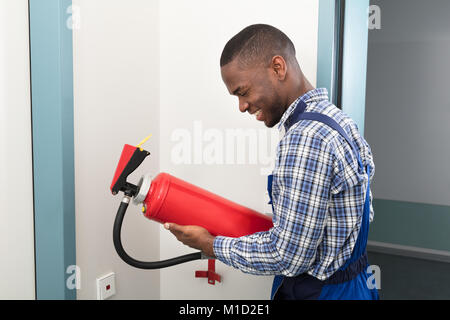 Happy Male African Professional Holding Fire Extinguisher Stock Photo