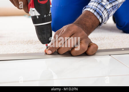 Person Hand Installing Carpet On Floor Using Wireless Screwdriver Stock Photo