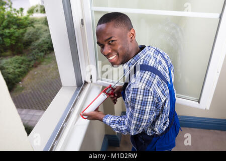 Close-up Of A Young Male Worker Applying Silicone Sealant With Silicone Gun Stock Photo