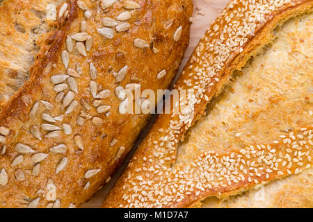 Close up on the crusts of two seed rolls, one with roasted sunflowers and the other with sesame in a close up full frame view Stock Photo