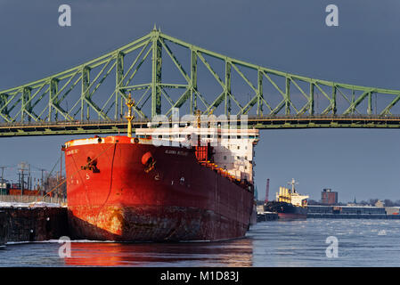 A container ship moored in Montreal Harbour with the Jacques Cartier Bridge behind Stock Photo