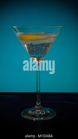 A tall glass of sparkling water with lemon on a blue background Stock Photo