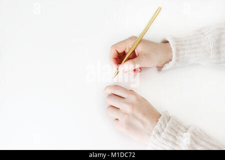 Woman's hands in sweater holding golden balpoint pen ready writing, drawing isolated on white background. Education concept. Styled stock image. Top view, flat lay. Stock Photo