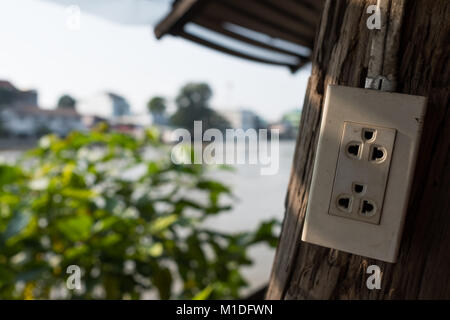Asian old electric plug with multiple socket outside on wooden wall. Stock Photo
