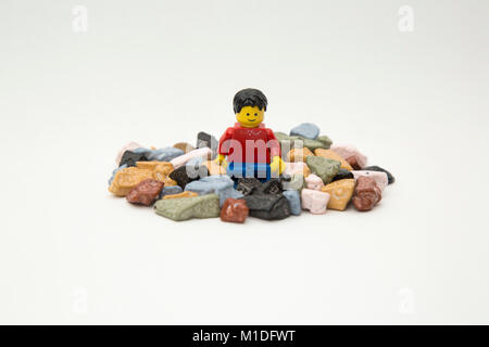 Larry the Lego guy sitting in a pile of chocolate rocks. Stock Photo