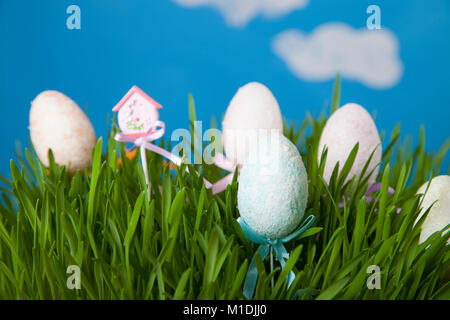 Easter still life with green grass and Easter eggs against the sky. Happy Easter. Easter greeting card. Stock Photo
