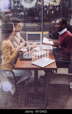 Glad three colleagues collaborating at cafe Stock Photo