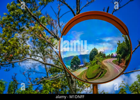 Mirror street sign reflection of the twisting and winding road from the rim top to the shore of Lake Maninjao, Sumatra Island, Indonesia Stock Photo