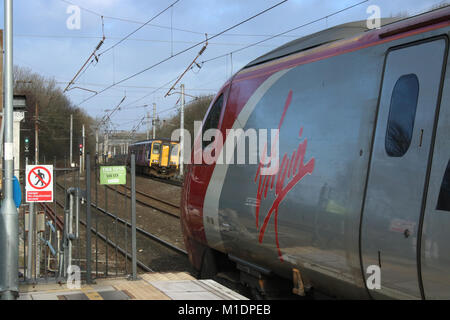 Virgin Pendolino electric multiple unit train at platform 3 Lancaster station on West Coast Main Line as a Northern dmu approaches platform 5. Stock Photo