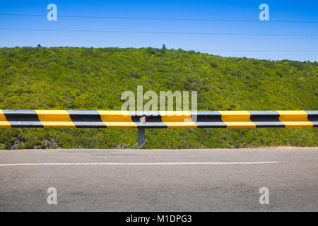 Striped yellow black traffic barrier on the side of mountain road in Portugal Stock Photo