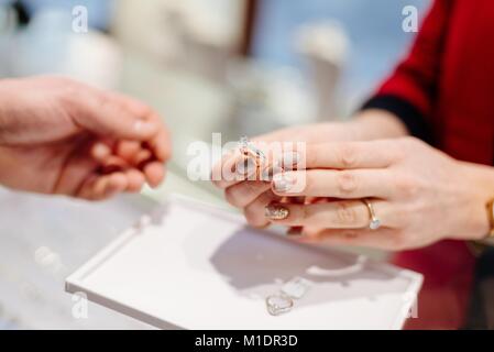 Female seller in a luxury jewelry store presents a ring. Buying a engagement ring. Jewelry store. Woman jeweler. Stock Photo
