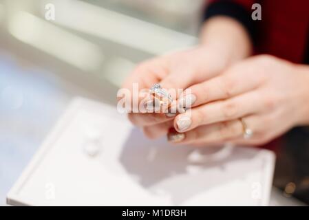 Female seller in a luxury jewelry store presents a ring. Buying a engagement ring. Jewelry store. Woman jeweler. Stock Photo