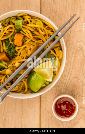 Yellow Thai Style Chicken Curry With Noodles and Sweet Potatoes On A Light Wooden Table Background Stock Photo