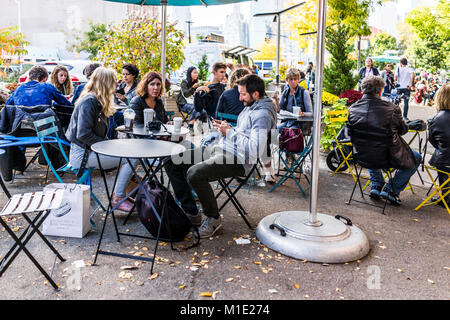 Brooklyn, USA - October 28, 2017: People crowd sitting eating famous restaurant food by cafe outside, Starbucks coffee drinking Stock Photo