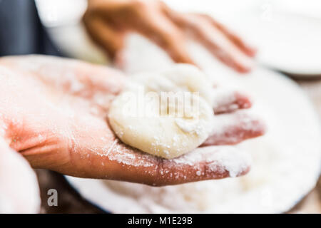 Hands shaping piece of mochi sticky glutinous rice cake dusted with starch flour to make dessert Stock Photo