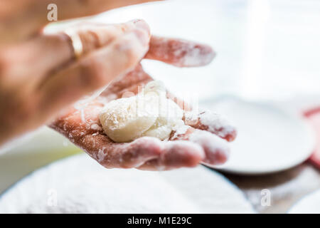 Hands shaping piece of mochi sticky glutinous rice cake dusted with starch flour to make dessert Stock Photo