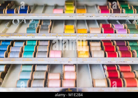 Colorful threads on spools closeup, sewing strings collection with many colors, organized in box shelf display Stock Photo