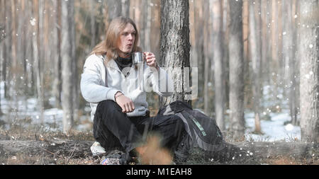 A man in a campaign drinks tea. A young traveler in the woods ca Stock Photo