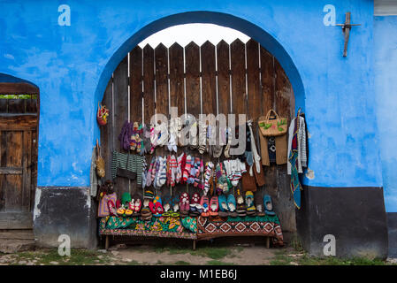 Winter season handmade, cozy, woolen knitted socks and booties for sale hanging on a wooden door. Viscri (Weisskirch) village, Transylvania, Romania Stock Photo