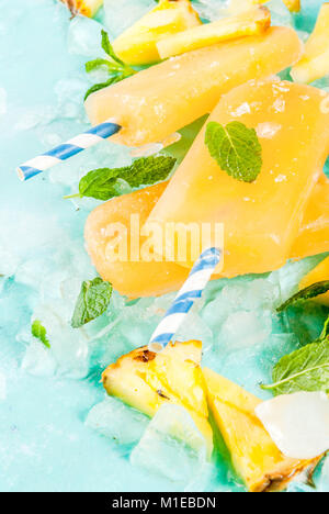 Homemade Pineapple Popsicles on Ice with fresh Pineapple slices and mint, on light blue background copy space Stock Photo