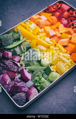 Cut Colourful Vegetables in a baking tray on a slate background Stock Photo