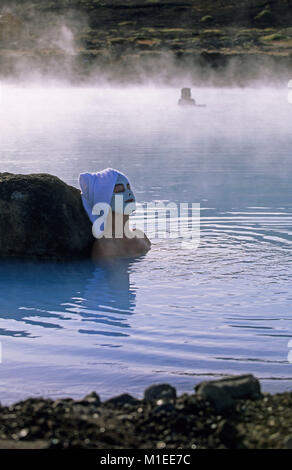 Iceland. Myvatn. Myvatn Nature Baths. Woman wearing beauty mask, towel on head, sitting in geothermal spa. Stock Photo