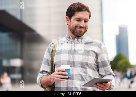 Man using a tablet and drinking coffee in the city Stock Photo