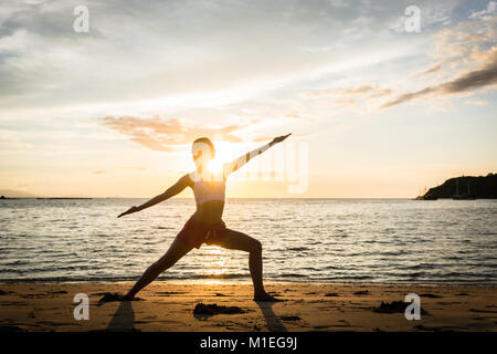 Silhouette of a fit woman practicing the warrior yoga pose again Stock Photo