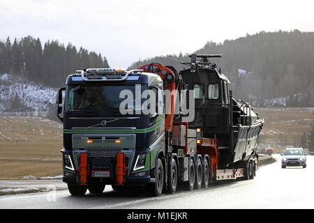 SALO, FINLAND - JANUARY 26, 2018: Volvo FH16 semi truck of Kuljetusliike Tauno Salminen Ky hauls a watercraft as wide load in South of Finland in wint Stock Photo