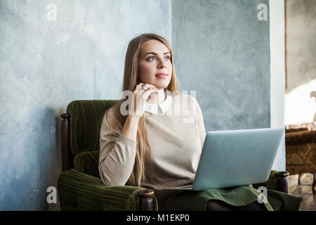 Cusual Young Woman with Laptop surfing the Web at Home Stock Photo