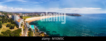 Emerald bondi blue colour of clean Pacific waters washing on wide sand of Bondi beach in Sydney. Wide aerial panorama of famous australian beach. Stock Photo