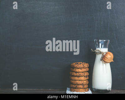 Fragrant cookies with chunks of chocolate and a jug of fresh milk on a black background Stock Photo