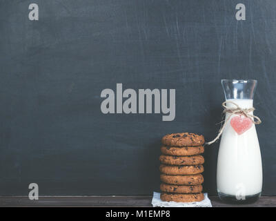 Fragrant cookies with chunks of chocolate and a jug of fresh milk on a black background Stock Photo