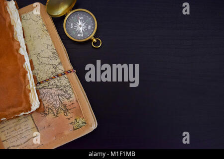 Old travel notebooks and compass placed on black wood surface Stock Photo