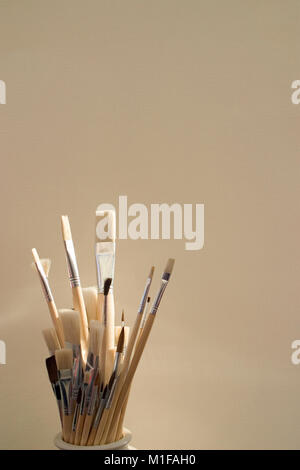 Artists paint brushes in pot in front of a plain background Stock Photo