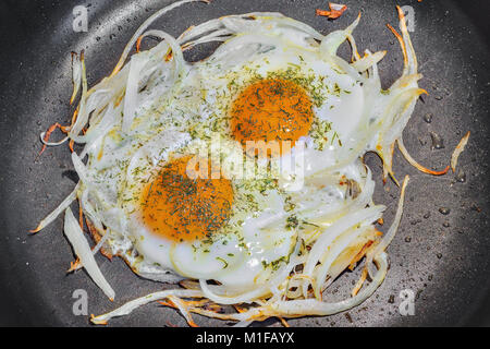 Fried eggs with onion and fennel on the pan. Stock Photo