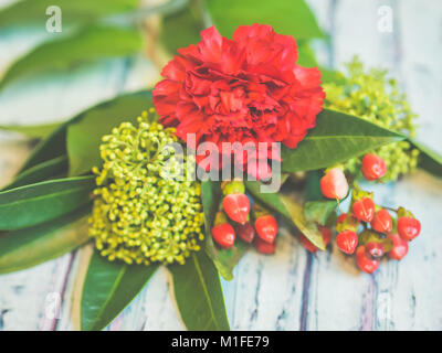 A bouquet of red and green flowers lying on a bluish wooden table shot against soft-focused background. Stock Photo
