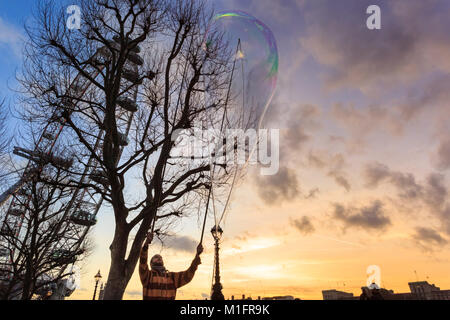 South Bank, London, UK, 30th Jan 2018. Jake, a bubble maker, or bubbler as he prefers to be called, entertains Londoners on the South Bank with huge, luminously coloured bubbles as the sun sets over the River Thames, London Eye, Westminster and South Bank. Credit: Imageplotter News and Sports/Alamy Live News Stock Photo