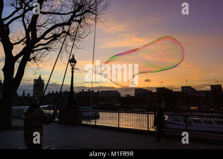 South Bank, London, UK, 30th Jan 2018. Jake, a bubble maker, or bubbler as he prefers to be called, entertains Londoners on the South Bank with huge, luminously coloured bubbles as the sun sets over the River Thames, London Eye, Westminster and South Bank. Credit: Imageplotter News and Sports/Alamy Live News Stock Photo