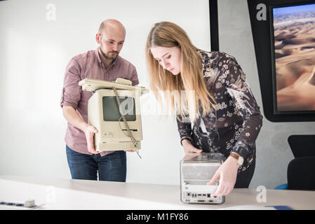Members of staff show Macintosh 128K, signed by Steve Wozniak, release date January 1984, and Power Mac G4 Cube, release date July 2000, at MacPaw's Ukrainian Apple Museum in Kiev, Ukraine on January 26, 2017. Ukrainian developer MacPaw has opened Apple hardware museum at the company’s office in Kiev. The collection has more than 70 original Macintosh models dated from 1981 to 2017. Stock Photo