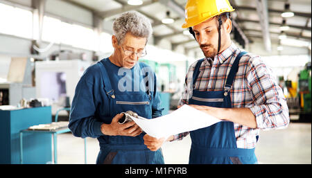 Engineer Teaching Apprentices To Use Computerized cnc metal processing machines Stock Photo