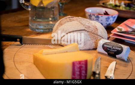 A farmhouse kitchen table set for a lunch of bread, cheese and salad. Stock Photo