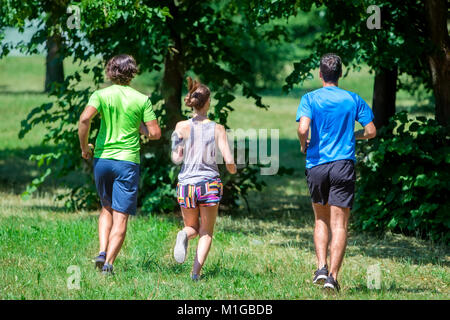 Woman and two young men running in the park at summer Stock Photo