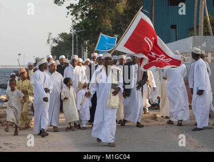 Sunni muslim people parading with flags during the Maulidi festivities in the street, Lamu County, Lamu Town, Kenya Stock Photo