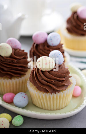 Easter vanilla cupcakes with chocolate frosting and candy eggs Stock Photo