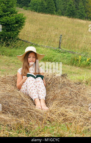 little girl reads a book in nature Stock Photo