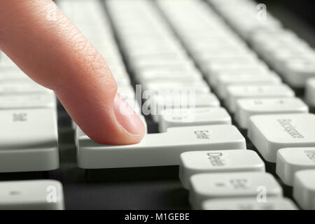 Finger pushing enter button on computer keyboard. Side view Stock Photo