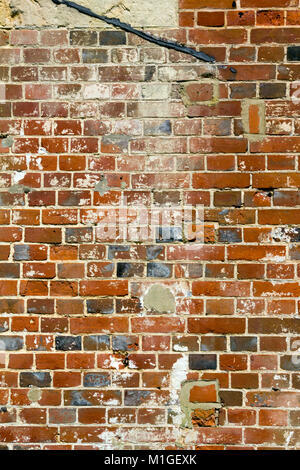 Old badly damaged and badly repaired red brick wall close up full frame Stock Photo